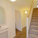 Carpeted staircase in modern hallway with mirror.
