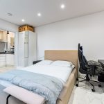 Modern bedroom with bed, desk, and kitchenette