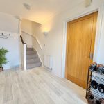 Modern hallway with staircase and wooden door.