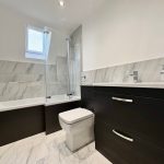 Modern bathroom with marble tiles and bathtub.
