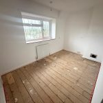 Empty room with wooden floorboards and window.