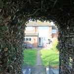Leafy tunnel view to a brick house garden