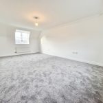 Spacious carpeted room with window and light fixture.