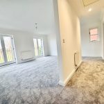 Bright, empty living room with carpet and French doors.