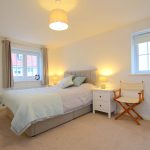 Bright bedroom with bed and two windows.