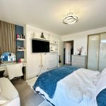 Modern bedroom with TV, dressing table, and bed.