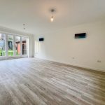 Bright empty room with wooden floor and garden view.