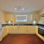 Modern kitchen with white cabinets and appliances.