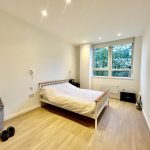 Minimalist bedroom with double bed and large window.