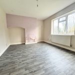 Empty room with wooden floor and large window.