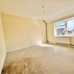Empty room with beige walls and a large window.
