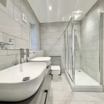 Modern bathroom with shower, twin sinks, and heated towel rail.