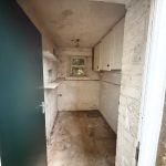 Small stone pantry with shelves and cabinets.