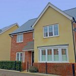 Modern two-storey UK house with yellow facade.