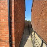 Narrow alleyway between two brick buildings, sunny day.
