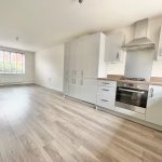 Modern kitchen with light wood flooring and appliances.