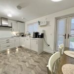Modern white kitchen with dining table and chairs.