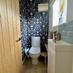 Stylish bathroom with floral wallpaper and wooden accents.