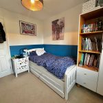 Cosy bedroom with bed and bookshelf.