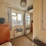 Bright bedroom with window, mirror, and wooden furniture.