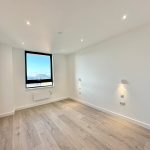 Bright empty room with wooden flooring and window.