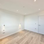 Empty white room with wooden floor and door