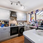 Modern kitchen with appliances and cluttered surfaces.