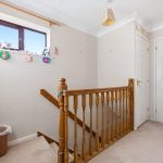 Bright landing with wooden banister and white doors