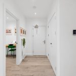 Minimalist hallway with wooden flooring and open doors.