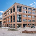 Modern brick office building with trees and cars.