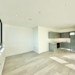 Modern empty kitchen with large windows and wooden floor.