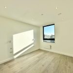 Bright empty room with wooden flooring, large window