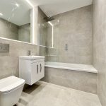 Modern tiled bathroom with shower and vanity unit.