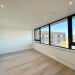 Bright empty room with large windows and wooden floor.
