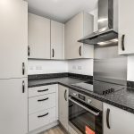 Modern kitchen with black countertops and appliances.