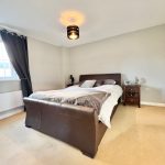 Modern bedroom with brown leather bed and bedside table.