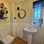 Modern bathroom with toilet, sink, and window.
