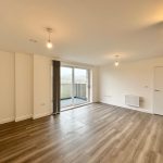 Spacious living room with balcony and wooden floor.