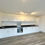 Modern white kitchen with fitted cabinets and appliances.
