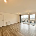 Spacious empty room with large window and balcony view.