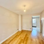 Empty room with light wood flooring and beige walls.