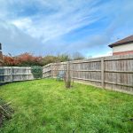 Fenced garden with green grass and patio chair.