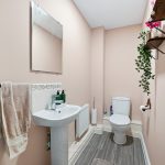 Modern bathroom with sink, toilet, mirror, and decor.