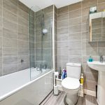 Modern bathroom with grey tiled walls and white fixtures.