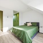 Modern bedroom with green accents and wooden flooring.