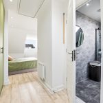 Modern bedroom with ensuite bathroom and green wardrobe.