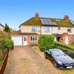 Suburban semi-detached house with solar panels and driveway.