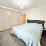 Modern bedroom with bed and fitted wardrobes.