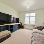 Modern living room with large TV and sofa.