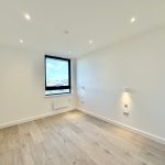 Spacious empty room with wooden flooring and window